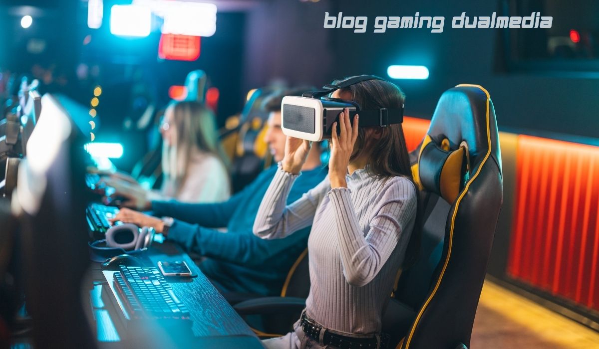 Young woman wearing a VR headset in a gaming lounge, sitting at a computer desk with other gamers using PCs, representing blog gaming dualmedia concept.