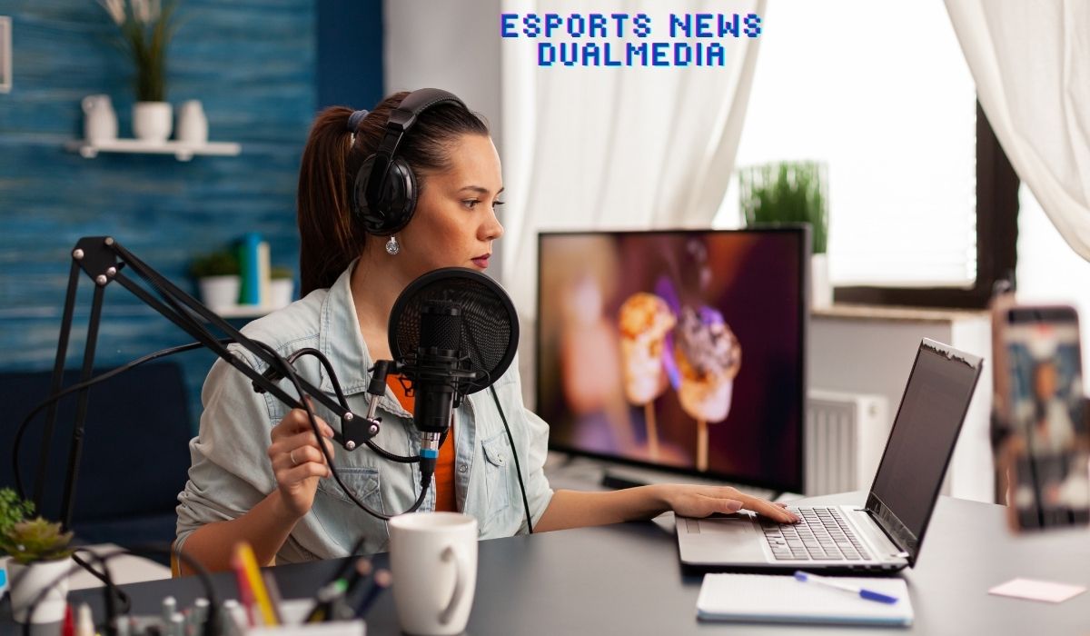 Female podcaster wearing headphones and speaking into a microphone while working on a laptop, creating esports news dualmedia content.
